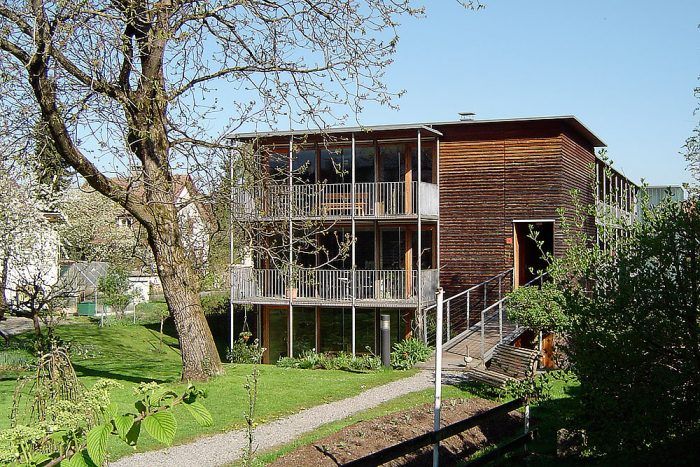 Trojpodlažný bytový dom v rakúskom Voralbergu je tiež postavený v pasívnom štandarde. Pre tento spôsob výstavby je typický kompaktný tvar s južne situovanými presklenými fasádami. Ďalším charakteristickým znakom je samostatne stojaca oceľová konštrukcia pavlačí na južnej a juhovýchodnej fasáde domu. Konštrukčné riešenie bráni vzniku tepelných mostov a pavlač má kumulovanú funkciu. Prepája interiér s exteriérom a zároveň je aj tieniacim prvkom veľkých zasklených plôch. 